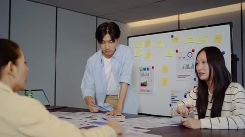 Marketing team brainstorming strategy in a office. Asian colleagues analyzing financial charts