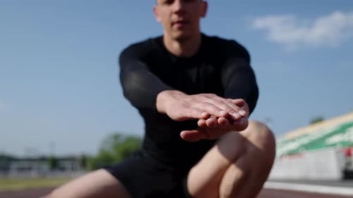 Athlete Stretching on Running Track on Sunny Day