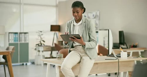 Young Woman Using Tablet Sitting on Desk in Office