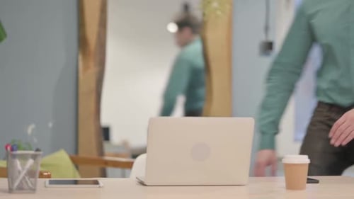Adult Man Sits at Desk and Opens Laptop