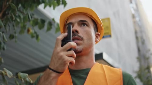 Serious Builder Communicating Walkietalkie Stepping City Closeup Hardhat Man