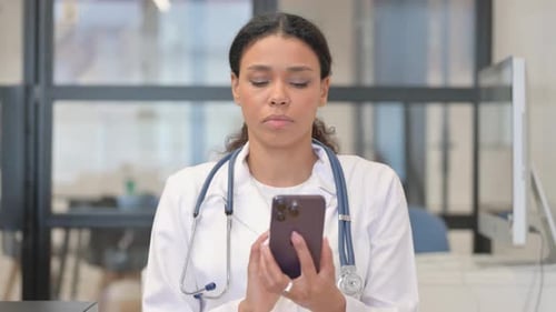 Woman Doctor Using Smartphone in Hospital Office