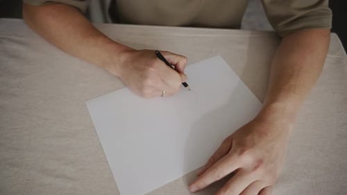 Person Drawing with Pencil on Paper Close Up