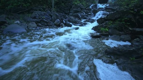 Low Angle Closeup of Waterfall Flowing Stream in a Dark Moody Forest