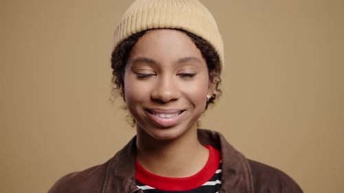 Smiling Woman Winking in Studio with Neutral Backdrop