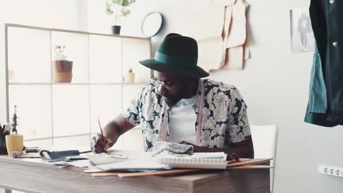Fashion Designer Sketching at Desk in Light Studio