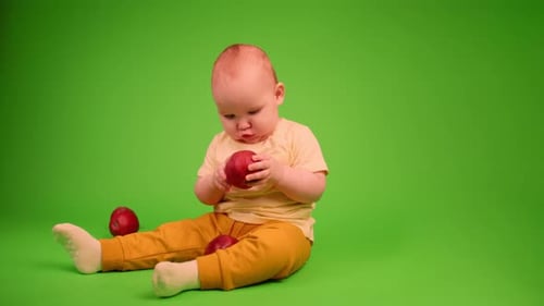Delightful Infant Eating Apple on Green Screen