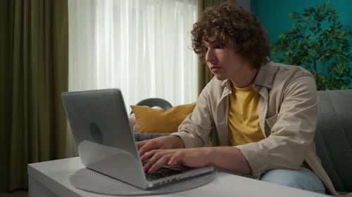 Young Man Typing on Laptop at Home