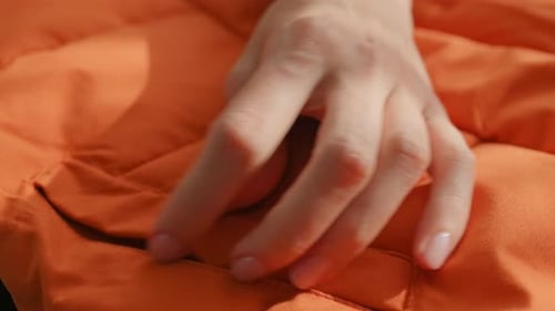 Hand Running Across Quilted Orange Jacket Material