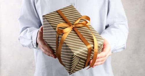 Hands Present Striped Gift with Gold Ribbon