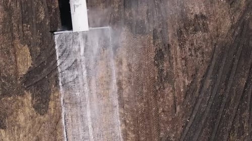 Ansicht von oben auf einen Ackerschlepper, der dem natürlichen Boden auf landwirtschaftlichen Flächen Kalk zufügt. Luftaufnahme