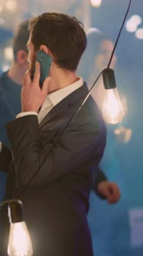 Jovem empresário caucasiano preocupado passando festa corporativa com colegas ligando para celular