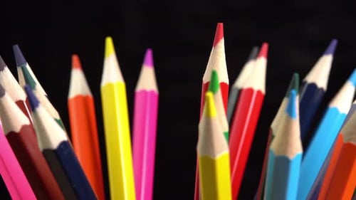 Colorful pencils rotate on black background. Rainbow pencils for drawing. Assortment of colored
