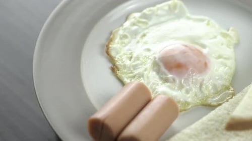 Close Up Shot rotating .Breakfast on a white plate on the right corner of the wooden floor.