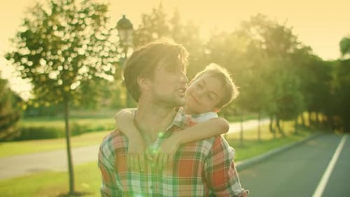 Smiling Father Giving Son Piggyback Riding Outdoors. Portrait of Young Man And