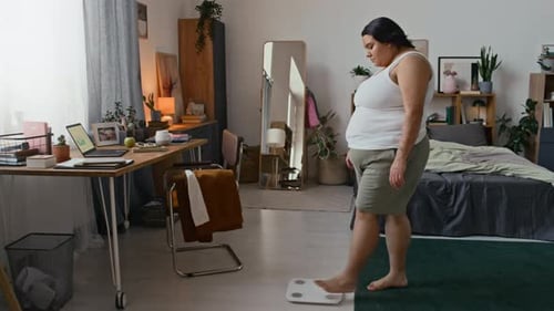 Mujer latina pisando una báscula en el dormitorio