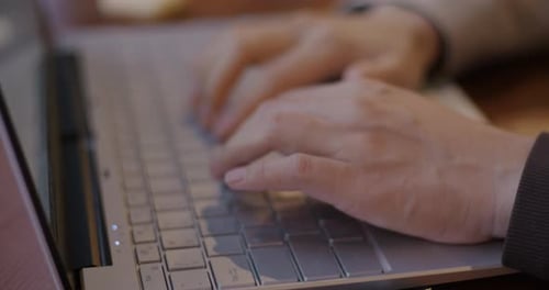 Closeup of Female Hands Typing with Laptop Keyboard While Businesswoman Working Online at Table