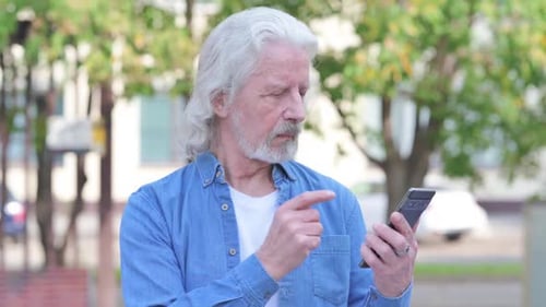 Senior Man Using Smartphone Outdoors During Daytime