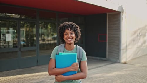 Smiling Student Holding Notebooks on College Campus
