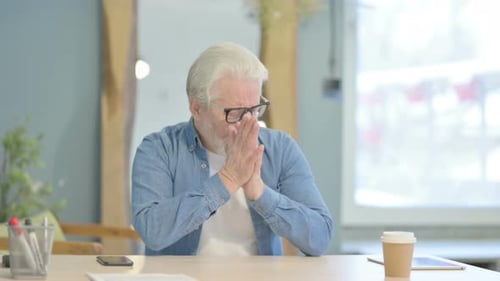 Senior Man Coughing While Sitting at Desk
