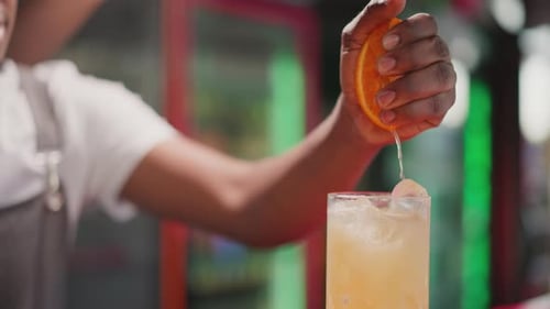 Close-up of Bartender Squeezing Fresh Orange into Cocktail