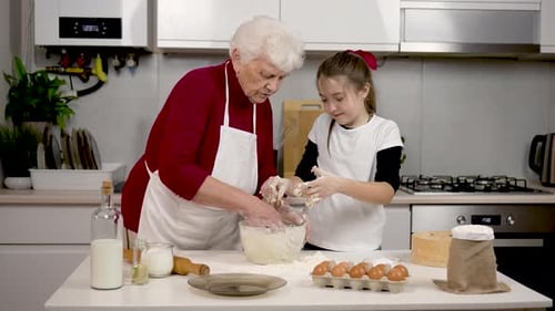 Attractive Mature Woman Wears Apron Standing in Cozy Kitchen Kneads Dough in Flour and Tells Cute