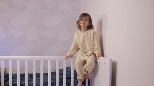 Portrait of a Little Girl Sitting on the Bed in Pajamas