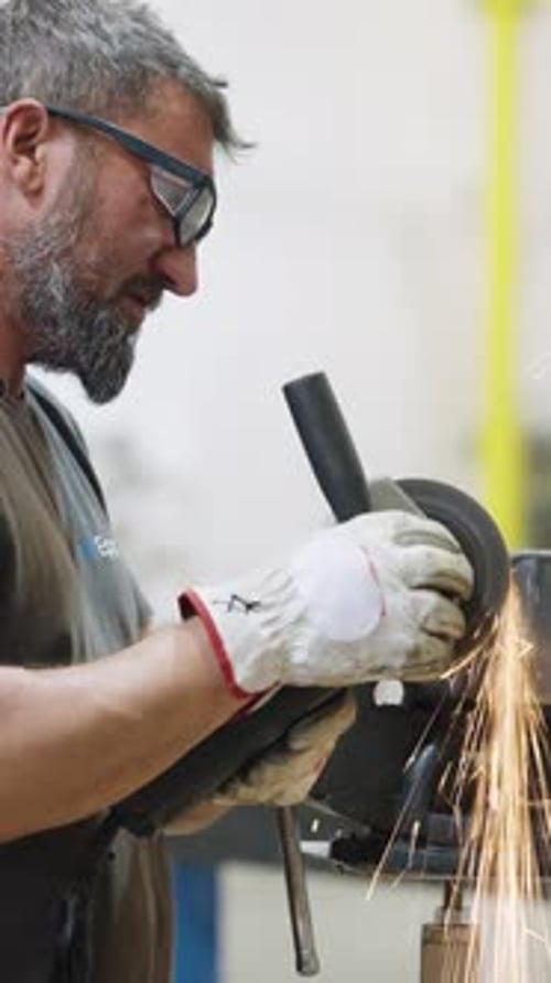 Metalworker Using Angle Grinder with Sparks Flying Vertical