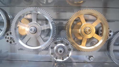 Set of silver and golden interlocked gears rotating to open a latch mechanism, Close up shot
