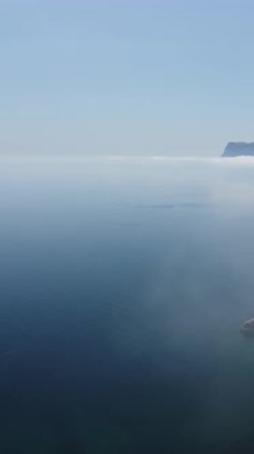Luftaufnahme Blauer Himmel, Sonne und Nebel über ruhigem Meer Die Drohne fliegt über neblige und flauschige Wolken Abstrakt