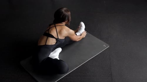 Woman is stretching body in gym. portrait and sport preparation. Young woman is stretching her leg