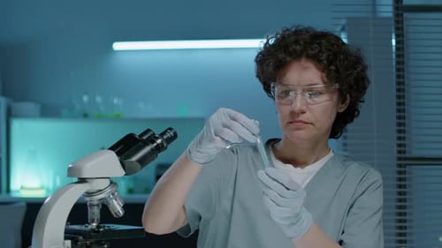 Woman Working in Laboratory with Microscope and Test Tube