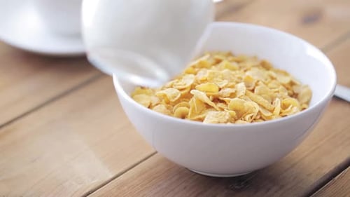 Breakfast, Food, Objects and Eating Concept - Milk Pouring to Corn Flakes