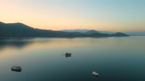 Aerial drone flying over a lake, water dam, with mountains at sunrise. Beautifull dreamy landscape