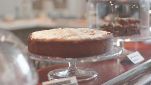 Organic cake with almond topping on a glass food stand dessert table with more cakes besides on a co