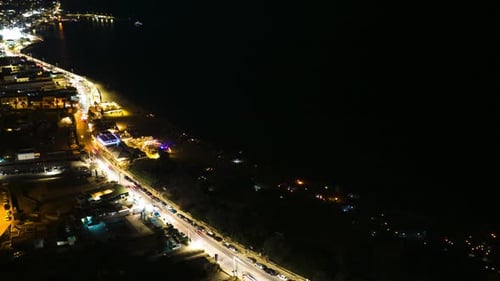 Dynamic 4K timelapse of the sea at night, with moving car lights along the coastal road