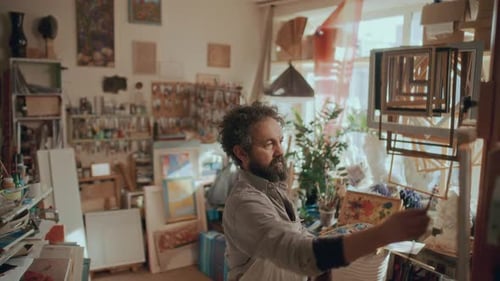 Painter Working in Sunlit Studio Surrounded by Art Supplies