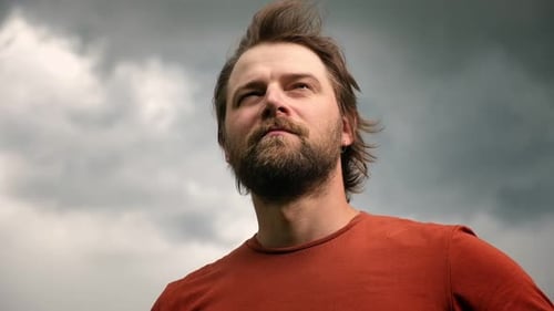Bearded Man Looks Upward at Cloudy Sky