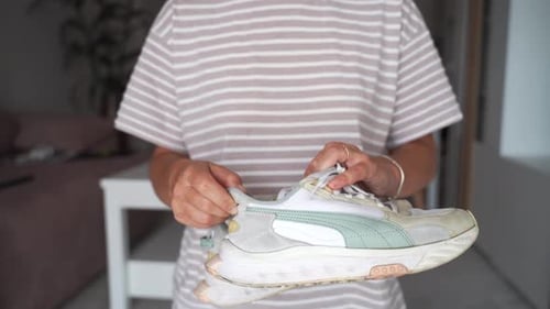 Woman Inspecting Sneakers and Giving Thumbs Up