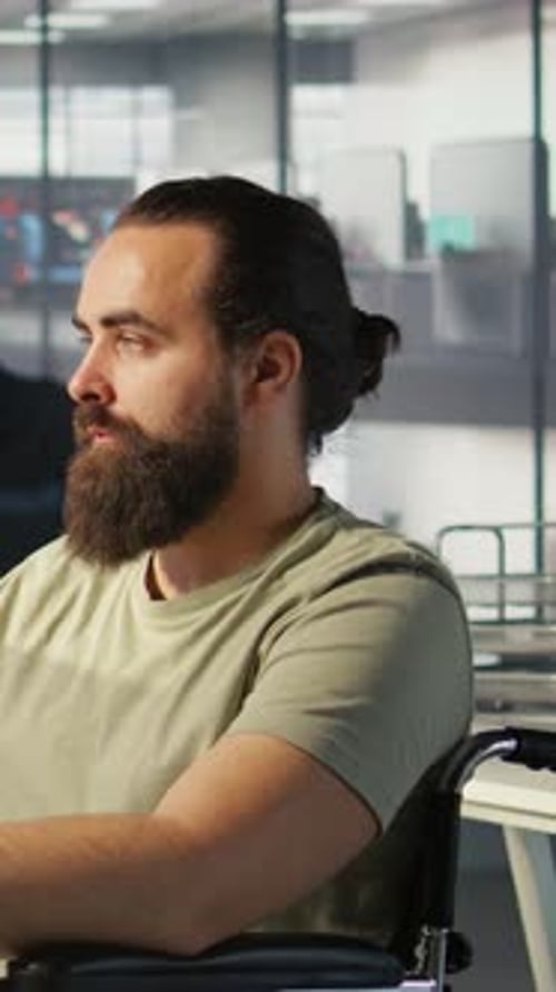 Adult Man in Wheelchair Sits in Modern Office