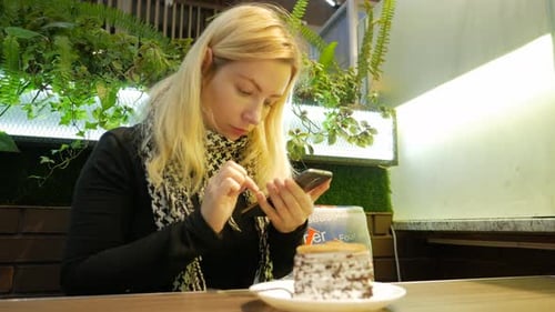 Young pretty blond hair girl siting at lounge cafe with cake and tea and works