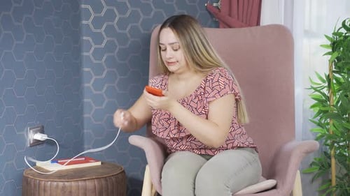 Woman Charging Phone and Relaxing in Chair