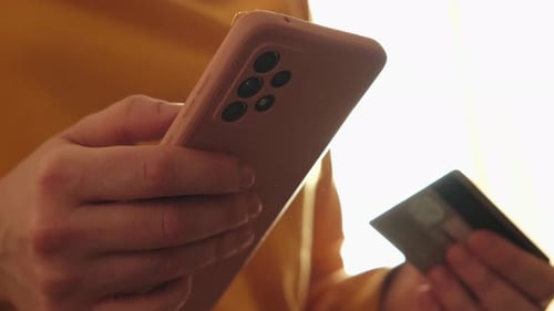 Mujer hace compras en línea con un teléfono inteligente pagando con tarjeta de crédito