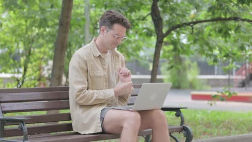 Man Using Laptop While Sitting on Park Bench