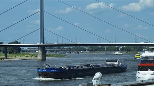 Barge Navigating River Underneath Modern City Bridge