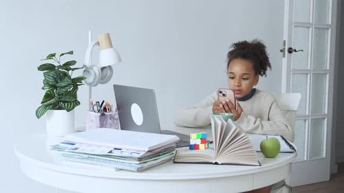 Child Studies At Table Using a Smartphone