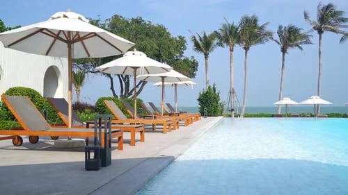 umbrella with bed pool around swimming pool with ocean sea background - holiday and vacation concept