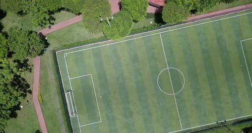 Revealing straight down shot in 4k of empty mini soccer field surrounded by park and trees in a gate