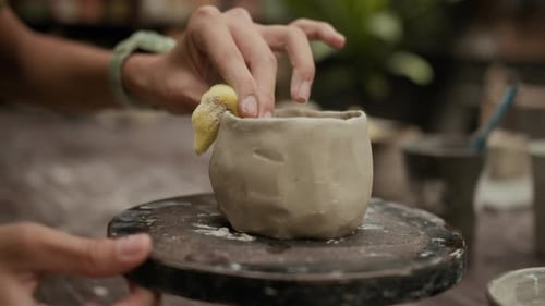 Hands of Sculptor Using Sponge on Clay Pot in Workshop