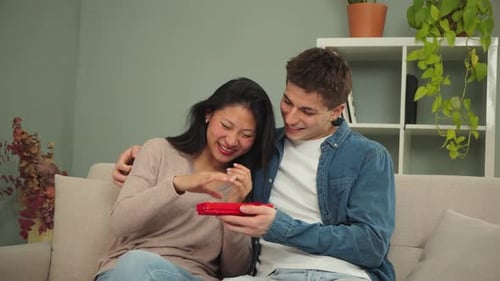 Surprise Gift Between a Young Couple on Couch